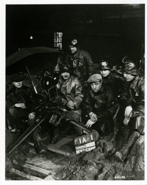 L’équipe du film, nombreuse, est postée derrière la Bell & Howell. Un homme à droite de la caméra tient un parapluie pour protéger l’appareil.