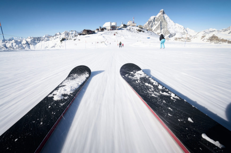 Deux skis en parallèle occupent les trois quarts du cadre. La neige semble striée, ce qui rend compte de la vitesse de glisse. La caméra est très proche du sol.
